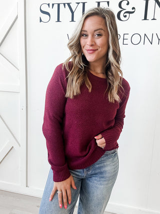 Woman wearing a maroon sweater and light blue jeans