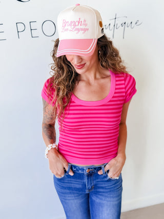Woman wearing a pink striped shirt and pink and white cap w