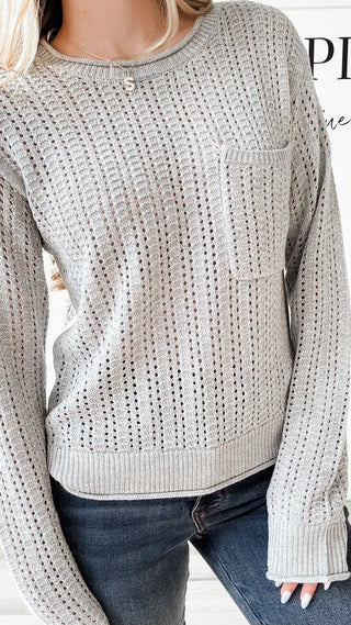 Person wearing a textured gray sweater with a pocket.