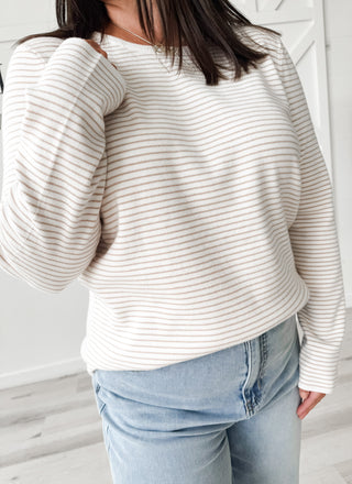 Ivory and brown striped sweater paired with light wash jeans.