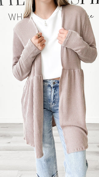 Person wearing a striped cardigan over a white shirt and jeans.