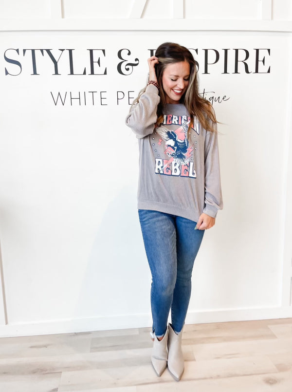 Crew neck. Drop shoulders. Long sleeves. Soft Ribbed fabric. Grey sweatshirt with American Rebel across the front in red and white letters