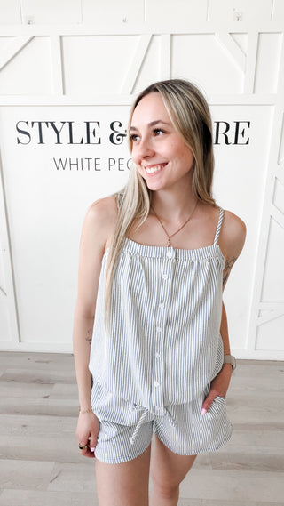 Woman wearing a blue striped top with a tie at the bottom 