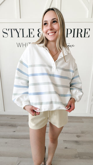 Woman wearing a striped quarter button up long sleeve. 