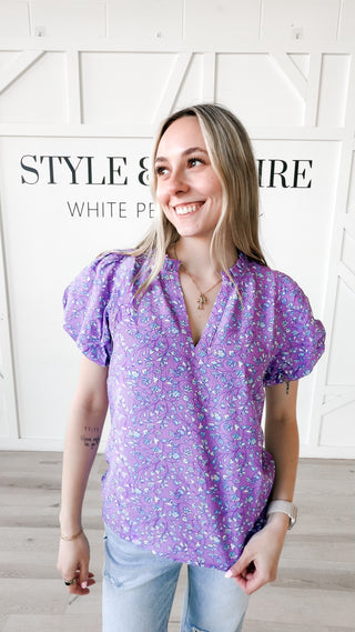 Woman wearing a purple floral blouse with text overlay on a white background