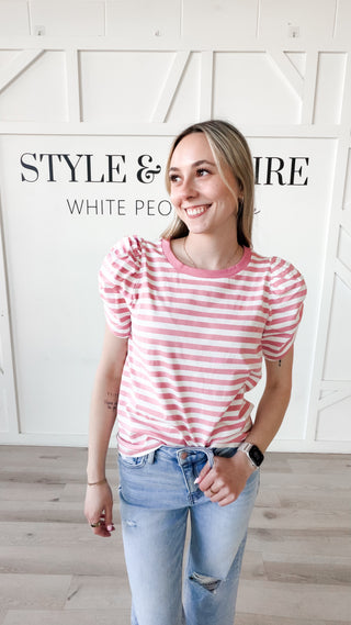 Woman wearing a pink and white striped shirt with puffy sleeves