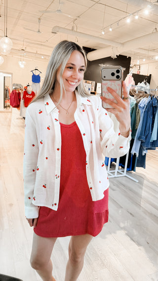 Woman wearing a oversized flowy shirt with embroidered cherries on it 