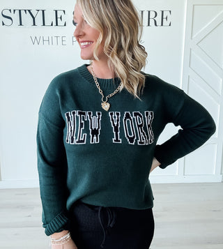 green sweater with "new york" stitched across the front in black and white